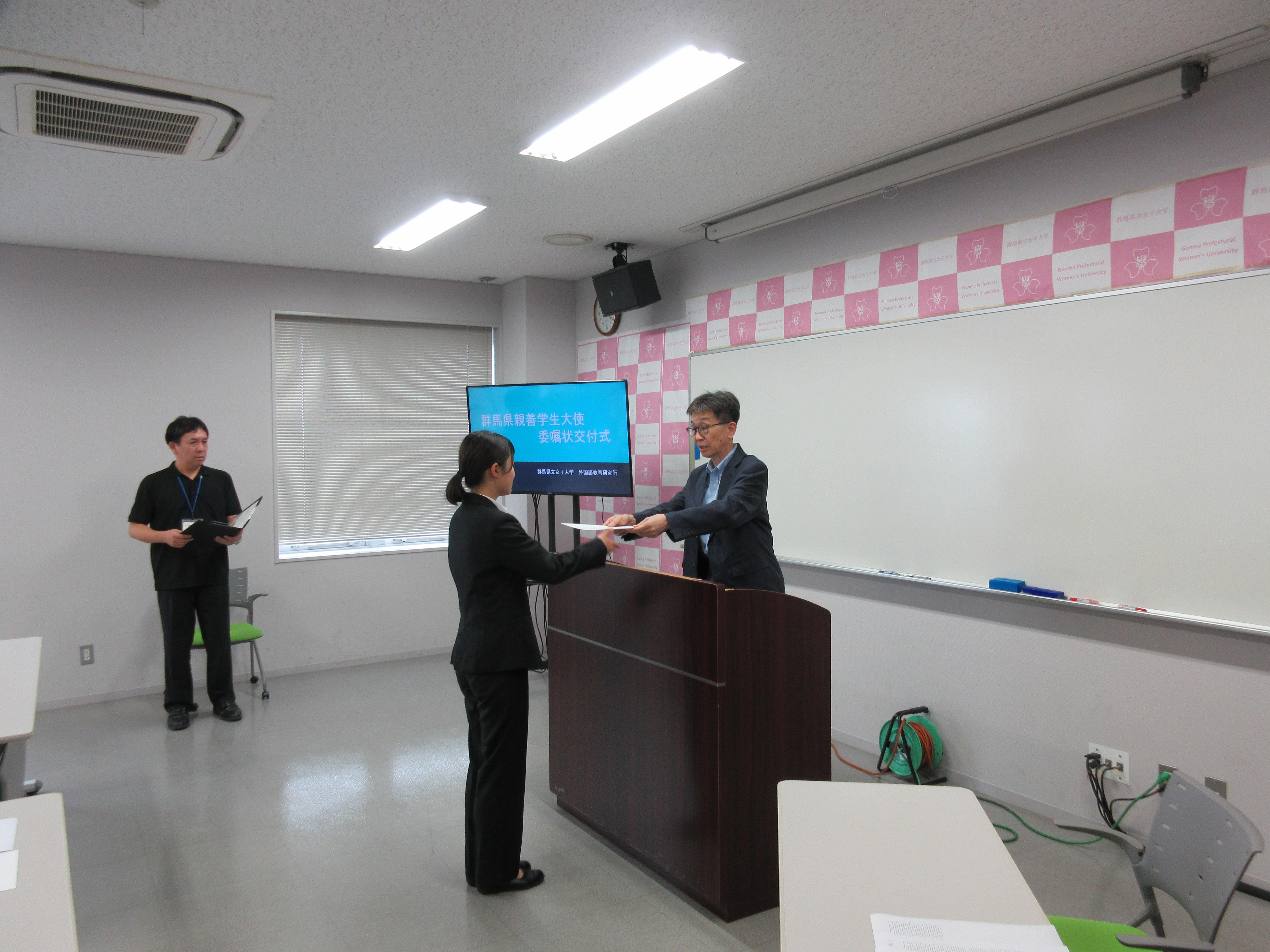 学生に群馬県親善学生大使委嘱状を渡す塩澤寛樹学長