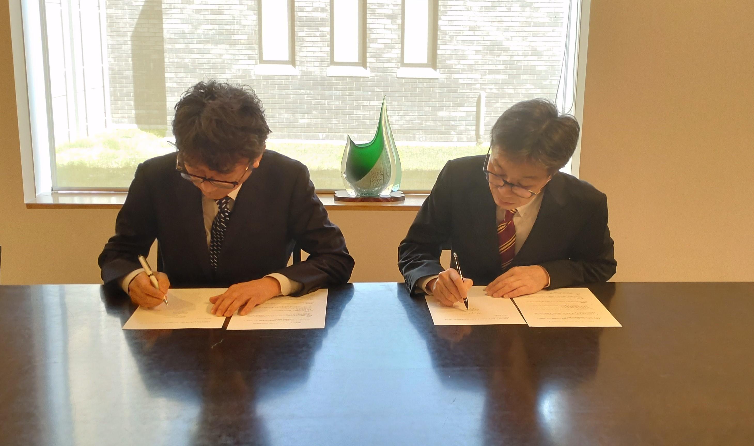署名する堀和行館長（左）と塩澤寛樹学長（右）