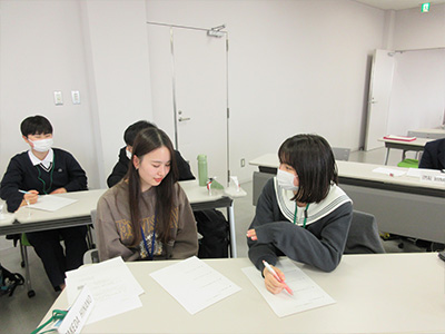 県立女子大学学生チューターのサポートを受けながら英語の活動をする塾生の様子